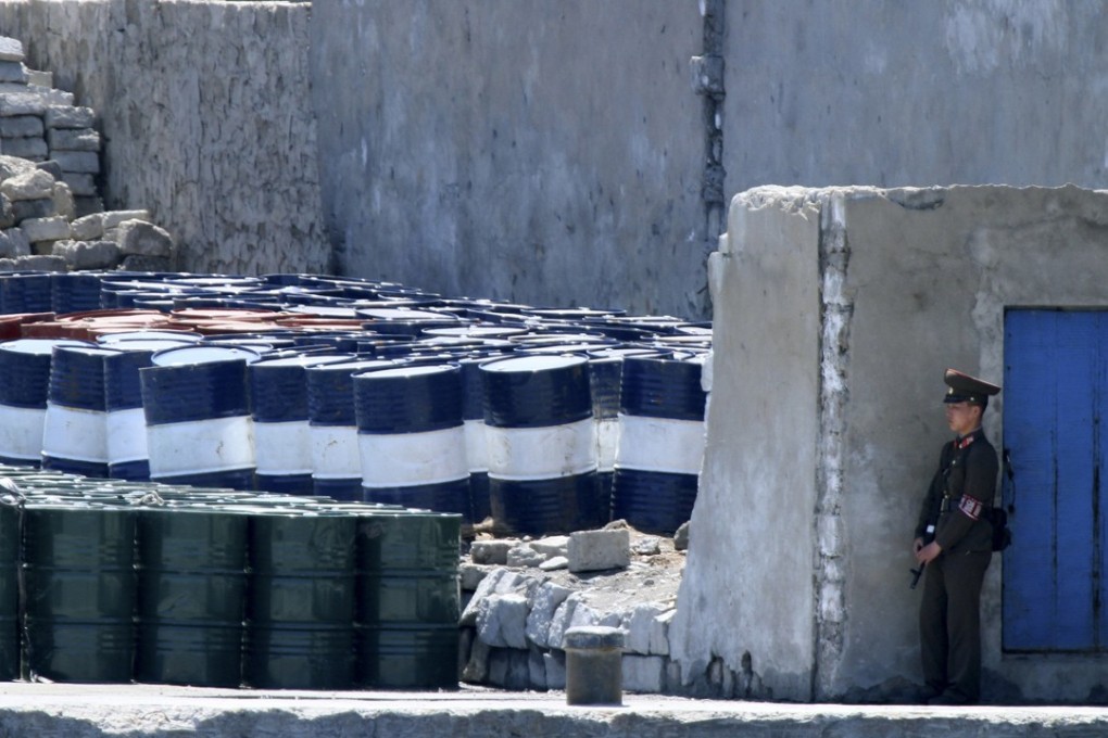 A North Korean stands guard near barrels in the border city of Sinuiju. According to Chinese customs data, the country did not export any oil products to North Korea in November. Photo: AP