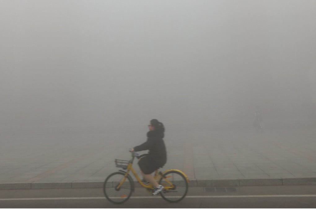 A woman cycles through the gloom in Jinan, capital of eastern China’s Shandong province, on Friday. Despite a government weather warning, many internet users blamed the poor air quality on pollution rather than fog. Photo: Reuters