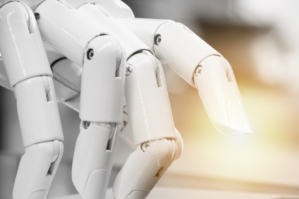 A robot’s fingers pointing to a laptop button. Photo: SHUTTERSTOCK