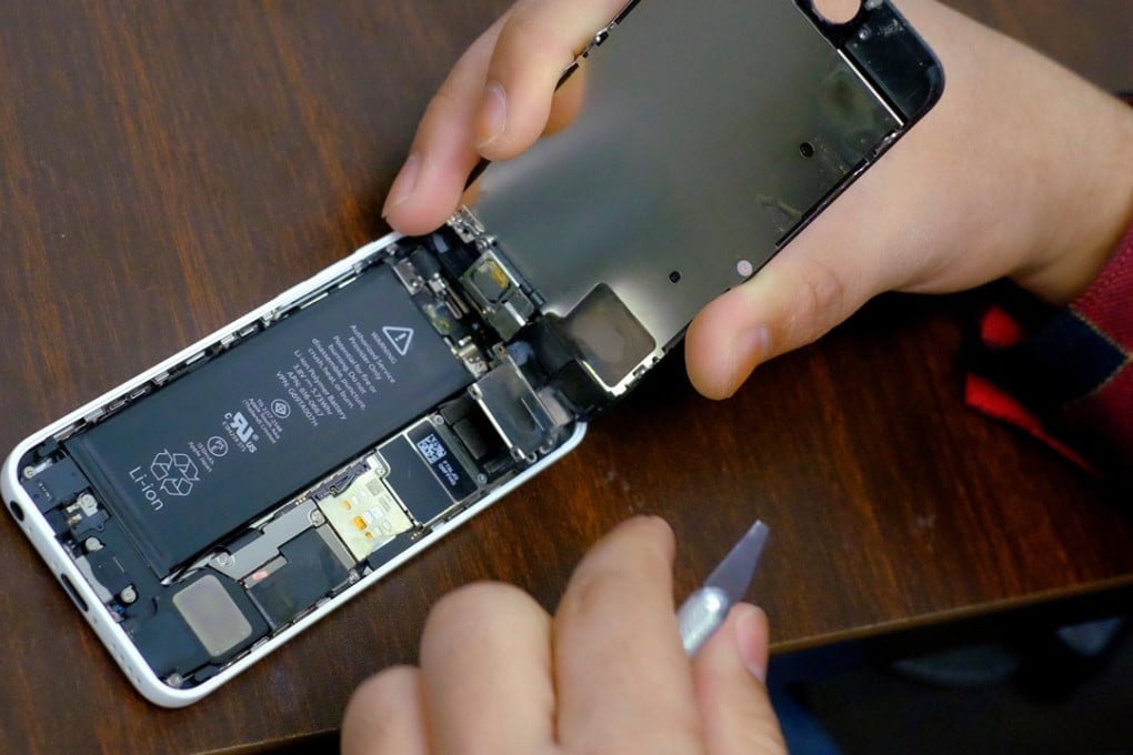 A battery is exposed as a man repairs an iPhone in a store in New York. Photo: Reuters