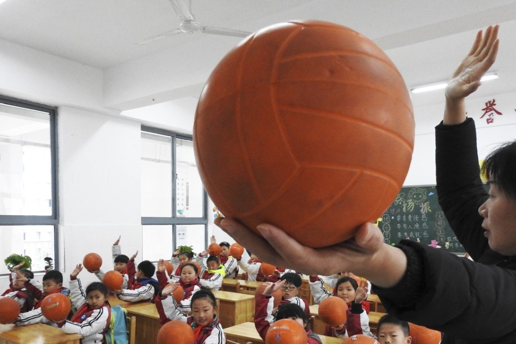 A teacher runs through some volleyball basics with pupils at a primary school in the city of Lianyungang, Jiangxi. Photo: ImagineChina