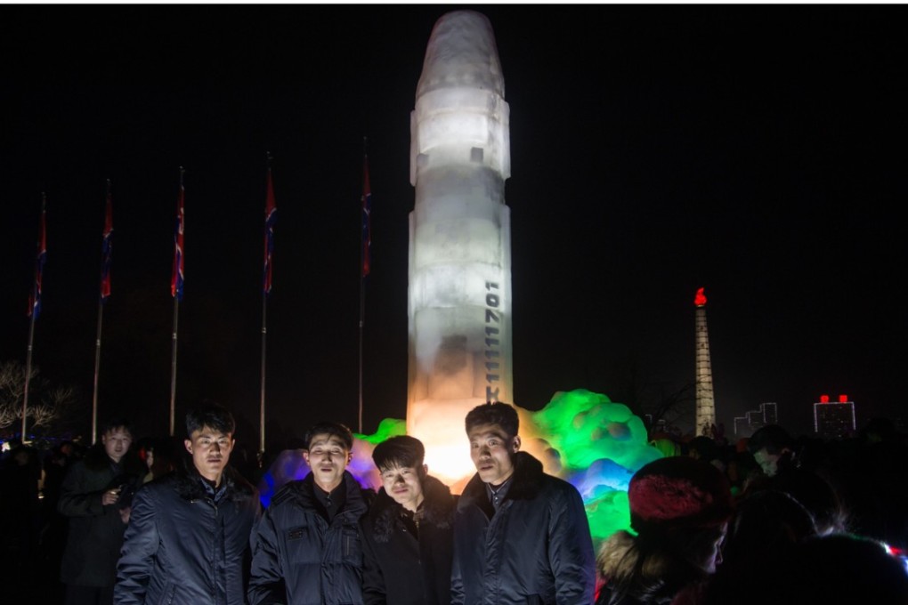 A group of men pose in front of before an ice sculpture depicting a Hwasong-15 intercontinental ballistic missile (ICBM) during new year celebrations at the Pyongyang Ice Sculpture Festival on Kim Il Sung Square in Pyongyang. Photo: Agence France-Presse