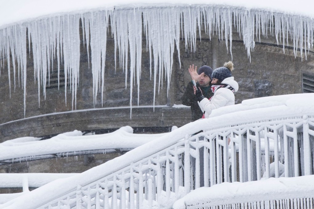 Visitors take photos outside an ice-covered building at Niagara Falls in Ontario, Canada, on Saturday. Photo: Xinhua