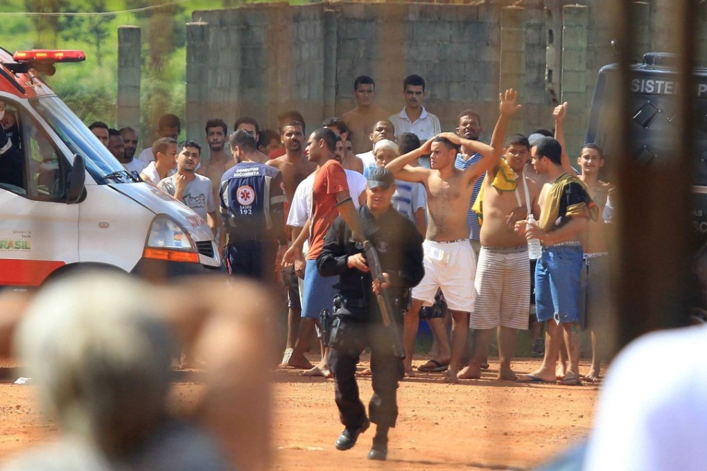 Inmates and armed guards are seen at a prison in Goiania, capital of the Brazilian state of Goias, on Monday after at least nine people died in a battle between rival gangs in the facility. Photo: EPA