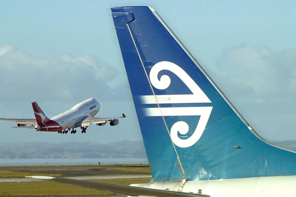An Air New Zealand Boeing 737 sitting at a departure gate while an Australian Qantas Boeing 747-400 takes-off from Auckland Airport in Auckland. Photo: AFP PHOTO/Dean TREML