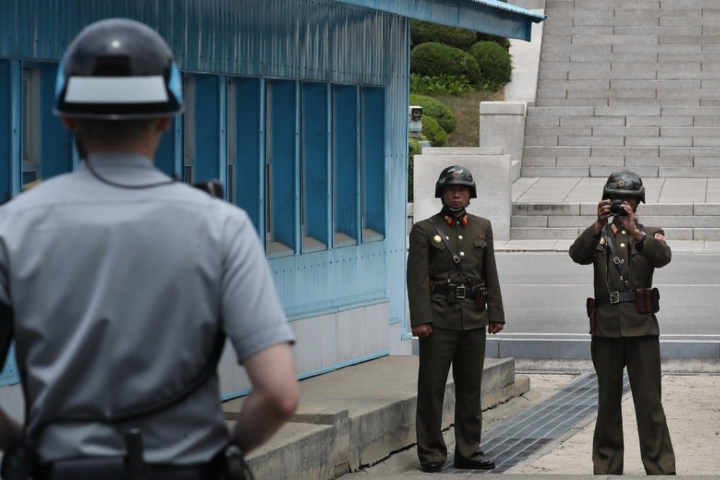 A North Korean soldier takes a photo of a South Korean soldier on guard just behind the military demarcation line. Photo: EPA