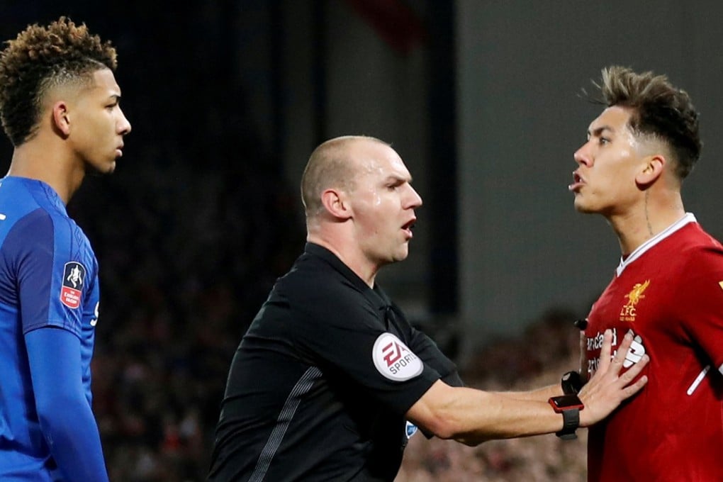 Referee Bobby Madley separates Everton’s Mason Holgate and Liverpool’s Roberto Firmino. Photo: Reuters