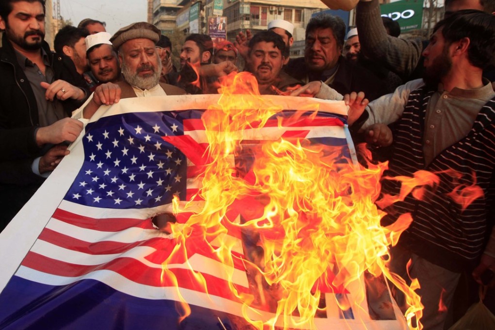 Pakistani traders shout slogans and burn a US flag with a picture of President Donald Trump during an anti-US protest in Peshawar, Pakistan. Photo: EPA