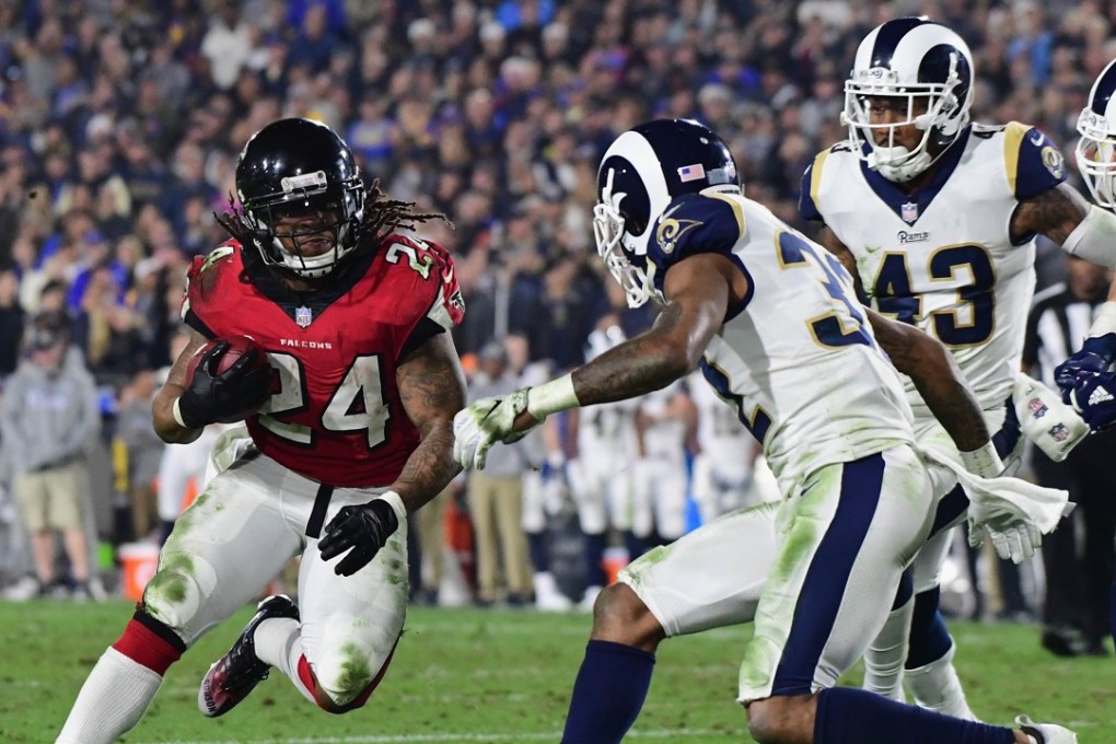 Running back Devonta Freeman of the Atlanta Falcons carries the ball in front of cornerback Troy Hill of the Los Angeles Rams. Photo: AFP