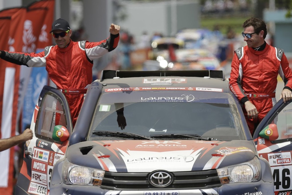 Toyota driver Andre Villas-Boas and his co-driver Ruben Faria, both of Portugal, stand on their footboards during the Dakar Rally ceremonial start in Lima, Peru. Photo: AP