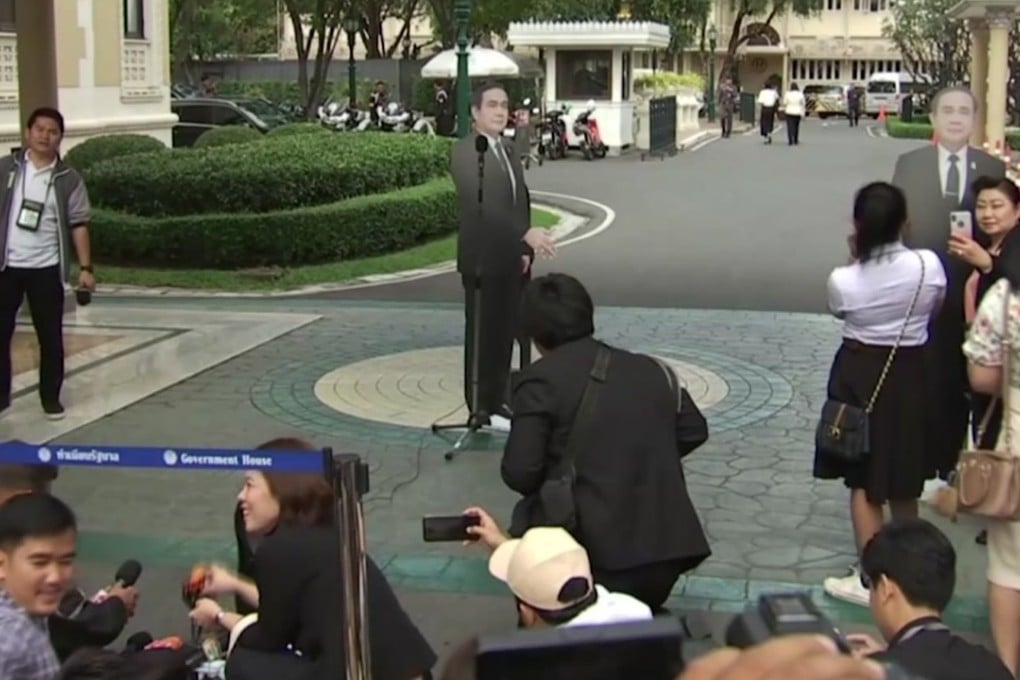 In this image from video, a life-sized cardboard cut-out figure of Thailand's Prime Minister Prayuth Chan-ocha, stands next to the microphone and faces the media after the Prime Minister left the scene, in Bangkok, Thailand, Monday Jan. 8, 2018. Prayuth evaded questions by bringing out a life-sized cardboard cut-out of himself, and telling reporters to "ask this guy" if they had "any questions on politics or conflict", he then turned on his heel and walked off, leaving the mock-up behind, to bemused looks and awkward laughter from the assembled media. (TPBS via AP)