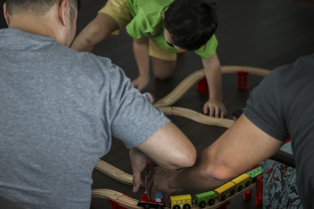 Shawn, left, James, right, and their son Noel, centre, play with a toy train they got Noel for Christmas. The two men are fighting for the right to keep in Singapore their son, the biological son of James and a surrogate mother in the United States. Photo: Don Wong