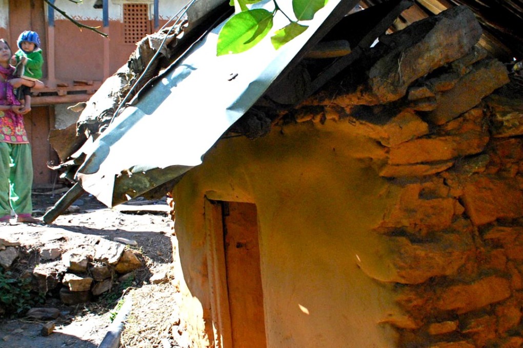 A Nepali woman looks down at a menstruation hut, where she would spend days on end while she shed blood. Photo: Bibek Bhandari