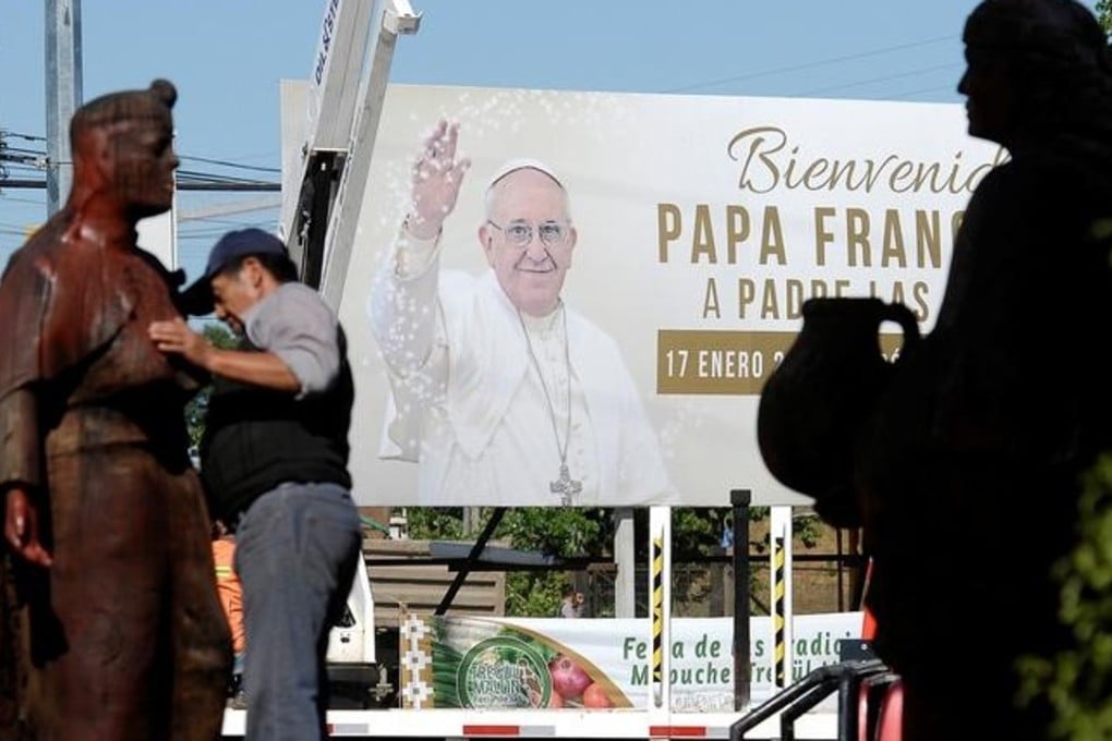 A man cleans a Mapuche sculpture in front a banner reading 'Welcome Pope Francis” ahead of the papal visit, in Temuco, Chile, on January 10, 2018. Photo: Reuters