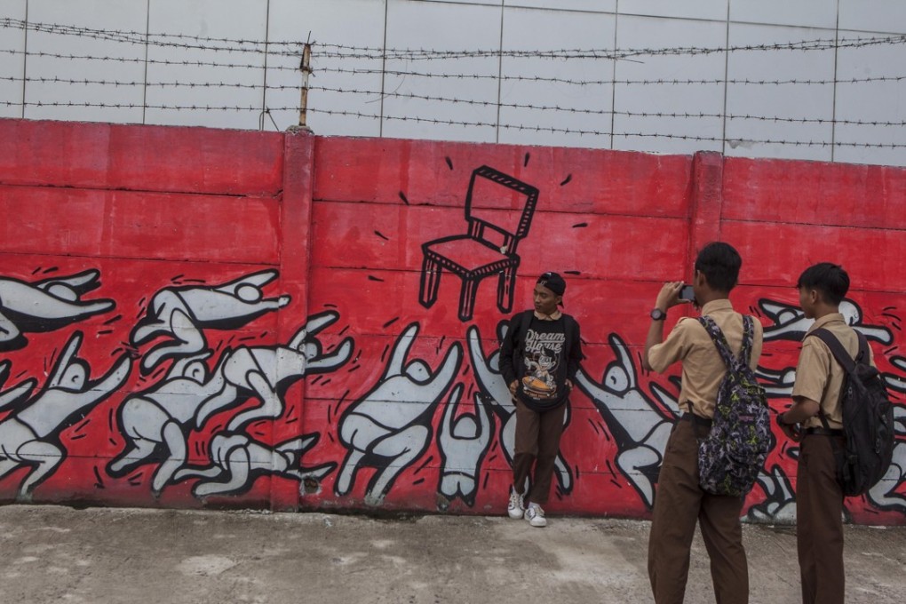 Students take photos in front of a mural by Popo in Jakarta, Indonesia. Photo: Agoes Rudianto