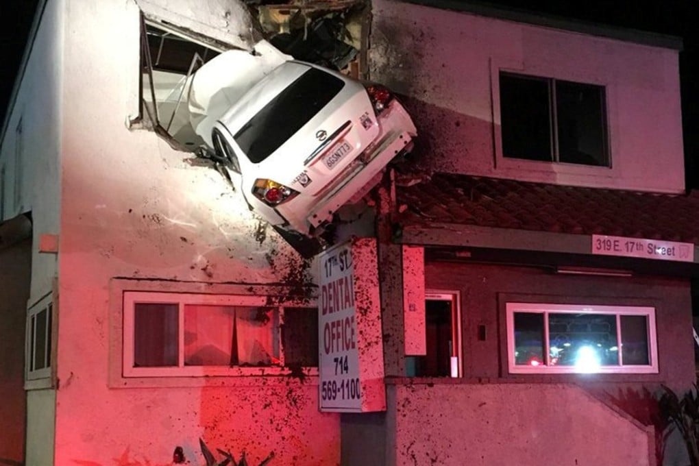 A car dangles off the second floor of a building after speeding into a median and going airborne in Santa Ana, California, on Sunday. Photo: Reuters