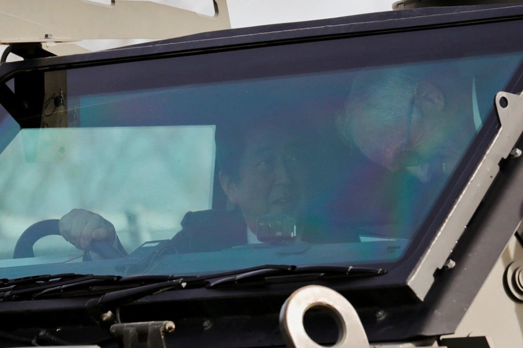 Australian Prime Minister Malcolm Turnbull and Japanese Prime Minister Shinzo Abe ride in Bushmaster military vehicle at Narashino exercise field in Funabashi, east of Tokyo. Photo: Reuters