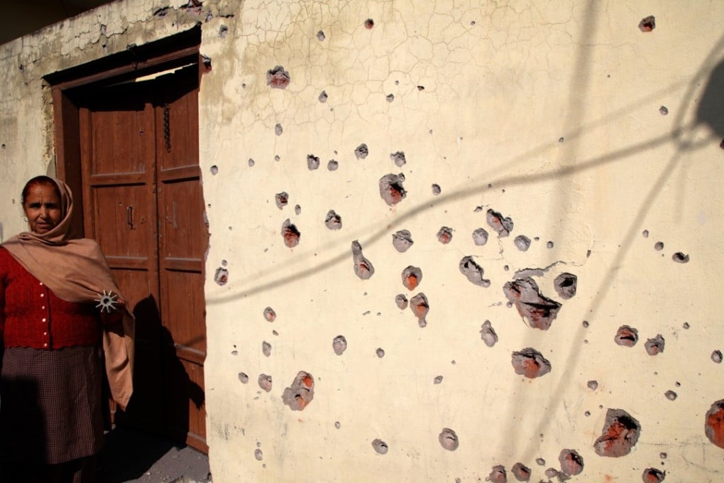 An Indian villager holds the tail unit of a mortar shell as she shows the shrapnel-ridden wall of a house damaged by alleged shelling from the Pakistani side of the disputed Kashmir border in the village of Arnia, about 45 km from Jammu on 19 January 2018. Photo: EPA-EFE
