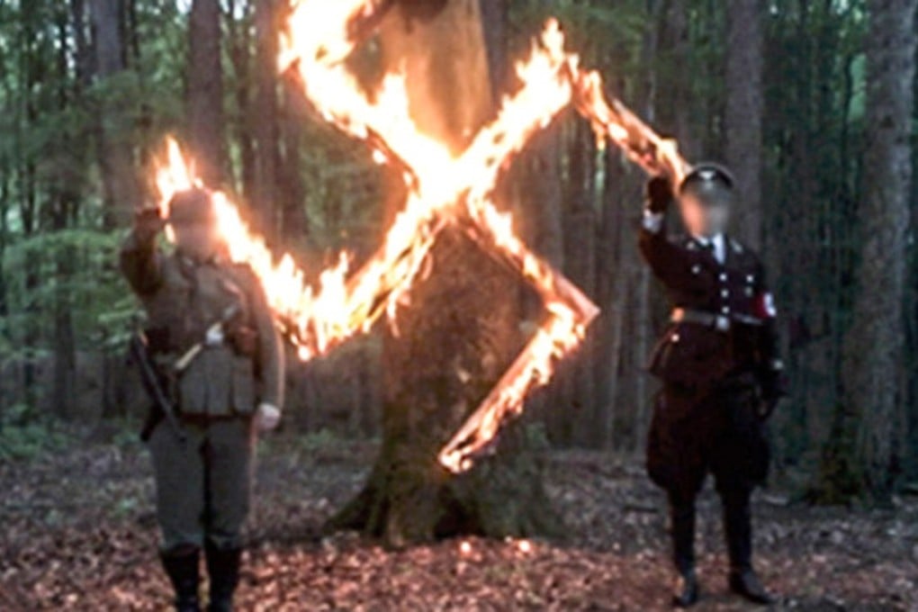 Two neo-Nazis burn a swastika in undercover footage recorded in Poland on April 20, 2017. The country – which was invaded, occupied and prutalised by Nazi Germany – has reacted in horror at the newly aired footage. Screengrab: TVN24