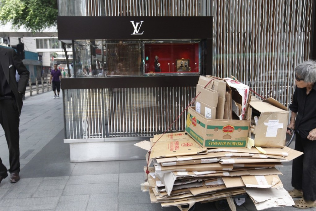 An elderly woman pushes a trolley with cardboard for recycling past a luxury designer boutique in Central in 2012. The Teresa Cheng scandal has once again drawn attention to the wealth gap in Hong Kong. Photo: EPA