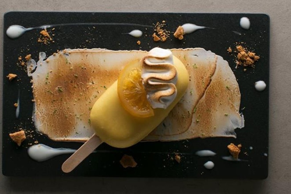 A frozen key lime ‘pie’ presented as an ice cream on a stick, sitting on a meringue smear with batons of sharp candied lemon at Old Manila in The Peninsula, Manila. Photo: Old Manila