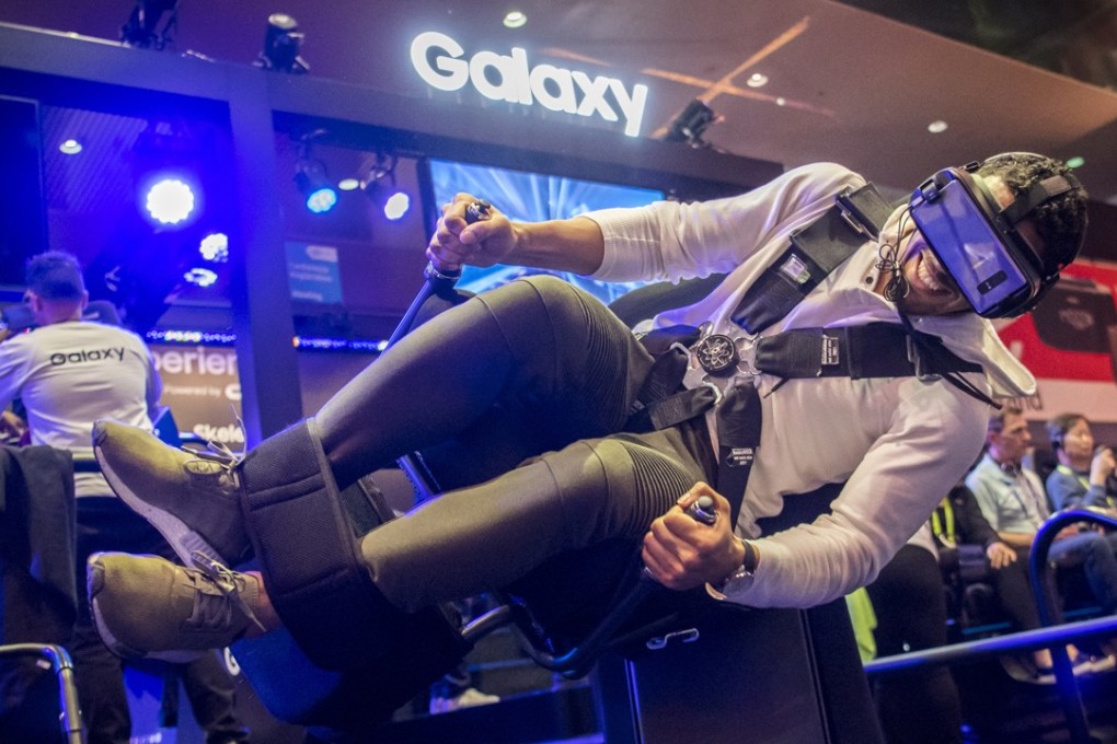 An attendee wearing a Samsung virtual reality headset rides the Flying Dino simulator during the 2018 Consumer Electronics Show in Las Vegas on January 10. Electric and driverless cars were a major part of this year's CES, as makers of hi-tech cameras, batteries and AI software vie to climb into automakers' dashboards. Photo: Bloomberg