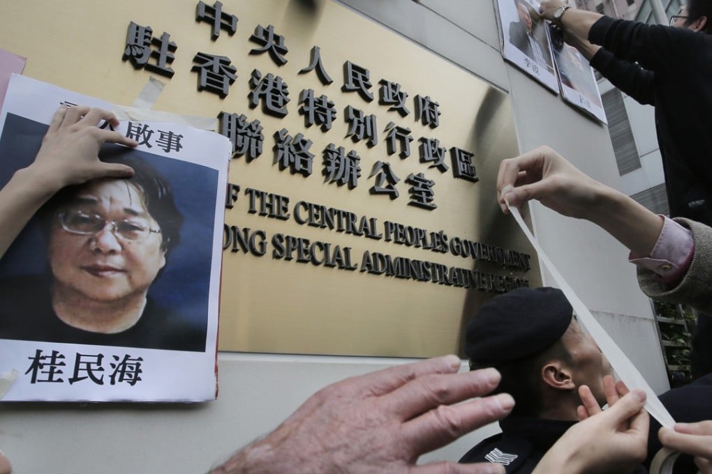 Protesters try to stick photos of missing booksellers, one of which shows Gui Minhai (left), during a protest outside the Liaison of the Central People's Government in Hong Kong. Photo: AP