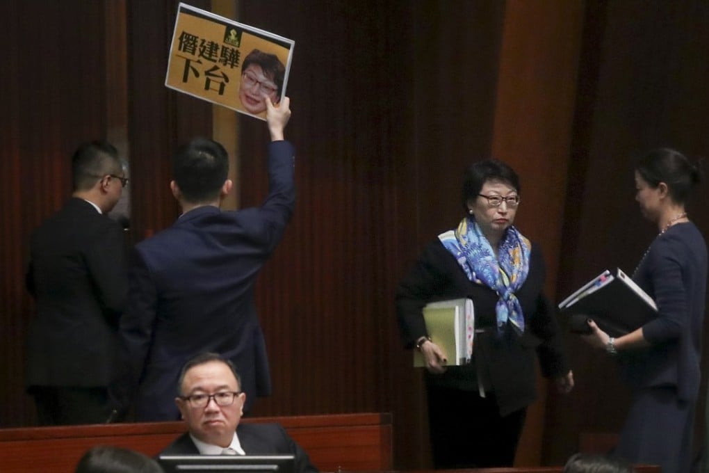 Lawmaker Raymond Chan Chi-chuen holds up a placard criticising Secretary for Justice Teresa Cheng as she arrives for a Legislative Council meeting, at Tamar on January 24. Photo: K.Y. Cheng