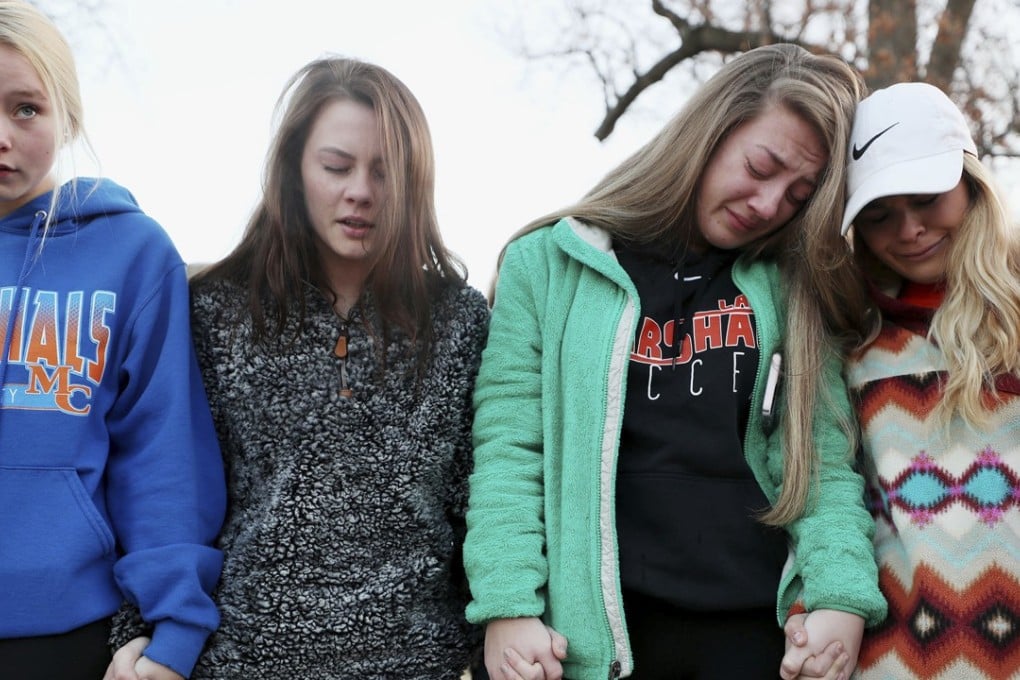 Students Brooklyn Boyce (second from right) and Katlyn Gamble (far right) cry as they hold hands with other Marshall County High School classmates during a prayer vigil for their injured and killed classmates on Wednesday. On Tuesday a 15-year-old boy opened fire in the school, police allege. He has been arrested. Photo: The Courier-Journal via AP)