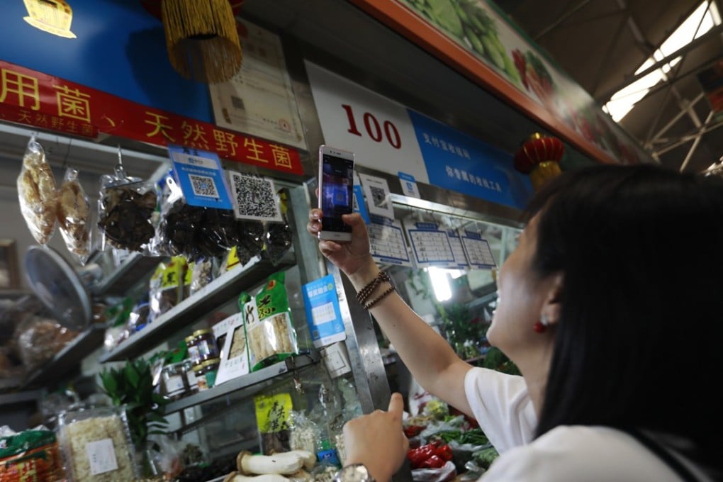 A woman scans an Alipay QR code to make a payment via her smartphone at a market in China. Annual mobile payment transactions in China are poised to grow further as many consumers and businesses in more than 600,000 villages across the country adopt cashless transactions. Photo: EPA