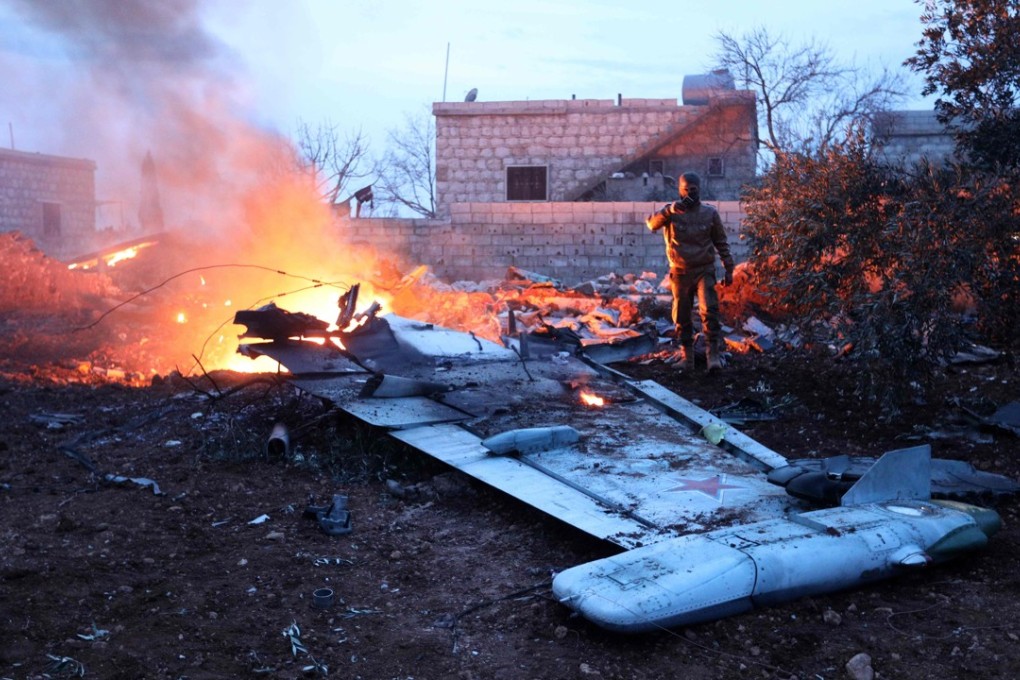 A rebel fighter taking a picture of a downed Sukhoi-25 fighter jet in Syria's northwest province of Idlib. Photo: AFP