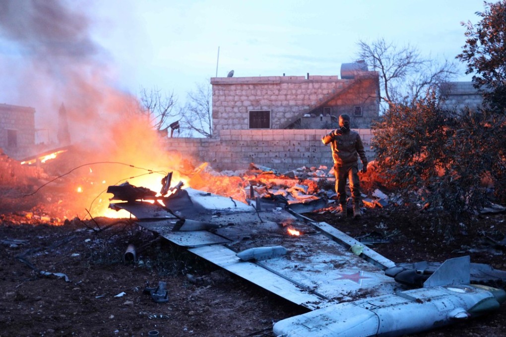 A Syrian rebel alongside the downed Sukhoi-25 fighter jet. Photo: AFP