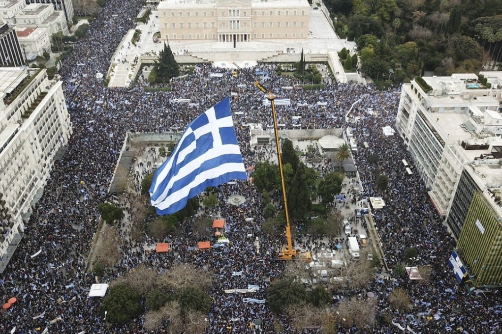 Protesters gather under a huge Greek flag flying from a crane, at the Athens’ main Syntagma square in front of the Greek Parliament during a rally in Athens on Sunday. Photo: AP