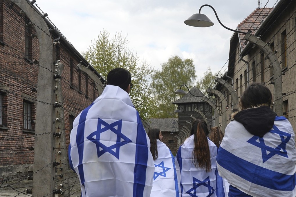 Participants in the yearly March of the Living walk between barbed wire fences in the former Nazi death camp of Auschwitz-Birkenau in Poland, on April 24, 2017. Jews from Israel and around the world marched the route from Auschwitz to Birkenau to commemorate Holocaust victims. A law recently passed by the Polish legislature would make it a crime to refer to such camps as “Polish”. Photo: AP