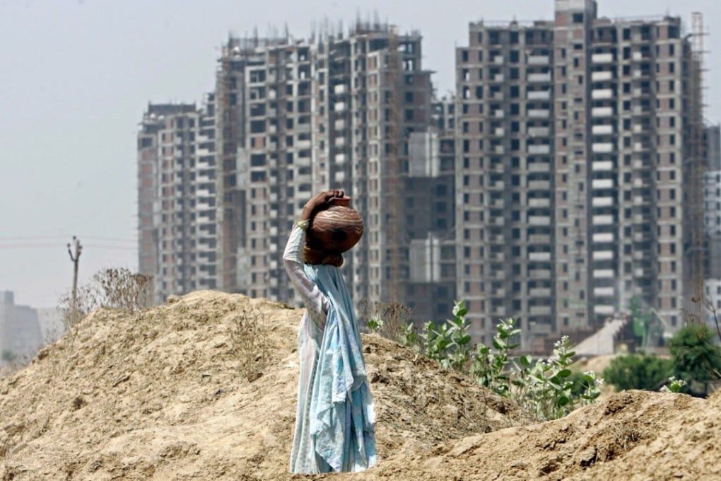 A village woman carries potted water as she walks in front of a backdrop of under construction high rise housing in Gurgaon, a suburb south of New Delhi on Wednesday, April 23, 2008. Photo: AP
