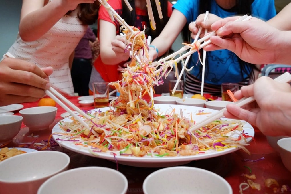 Diners toss yusheng ingredients for prosperity at a Lunar New Year feast.