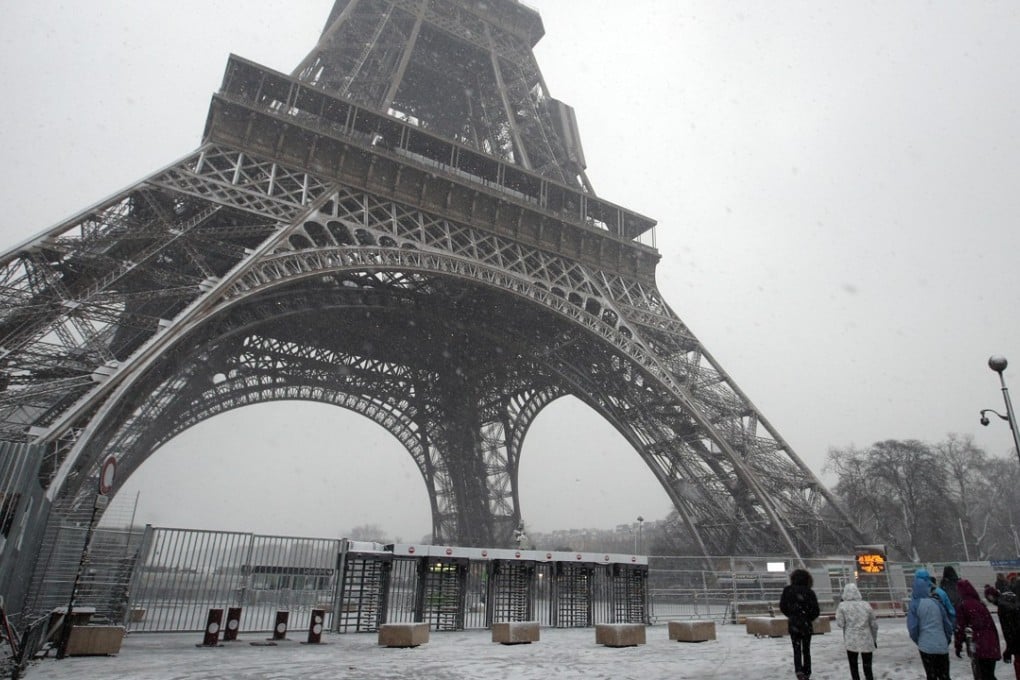 People walk under snow falling in Paris on Tuesday. Photo: AP