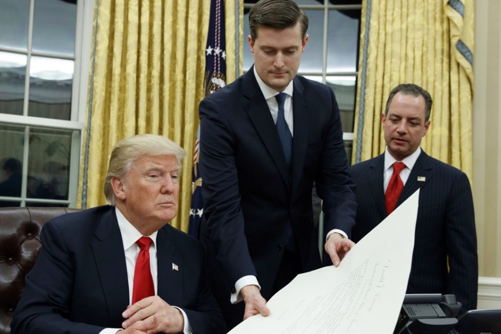 In this January 20, 2017 file photo, White House Staff Secretary Rob Porter, centre, hands President Donald Trump a confirmation order for James Mattis as defence secretary. Porter is stepping down following allegations of domestic abuse by his two ex-wives. Photo: AP