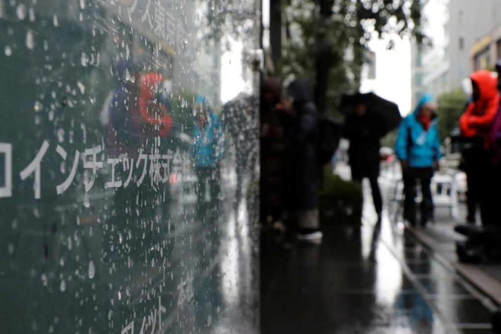 Journalists stand near to cryptocurrency exchange Coincheck’s sign. Photo: Reuters