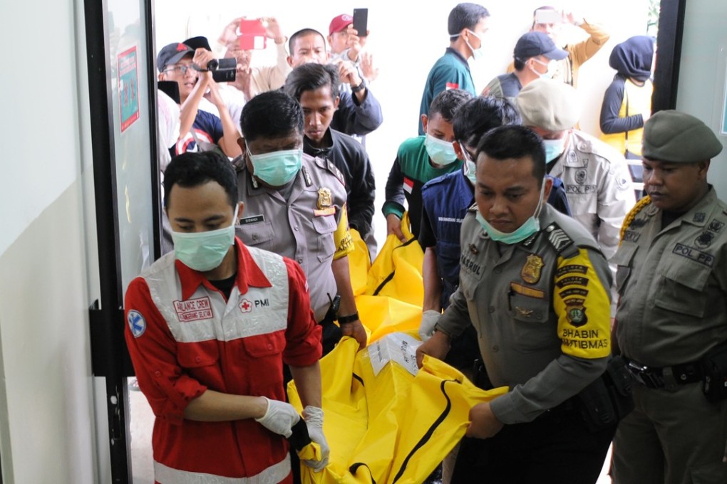 Indonesian police and ambulance crew carry the body of a victim of the bus crash. Photo: AFP