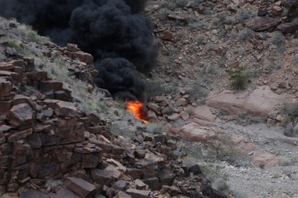 The fiery aftermath of a helicopter crash in the Grand Canyon on Saturday, that killed three British tourists. The identity of the person on the right is not known. Photo: Teddy Fujimoto
