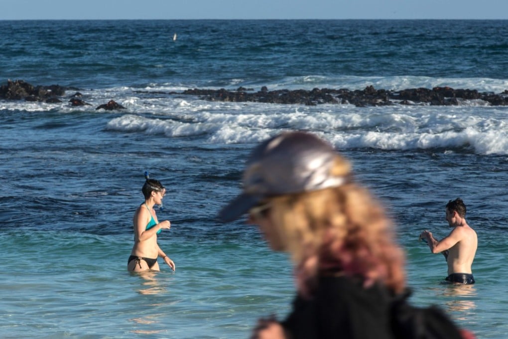 Tourists swim at Tortuga Bay beach in the Galapagos. Ecuador needs tourism dollars, but at what cost? Photo: AFP