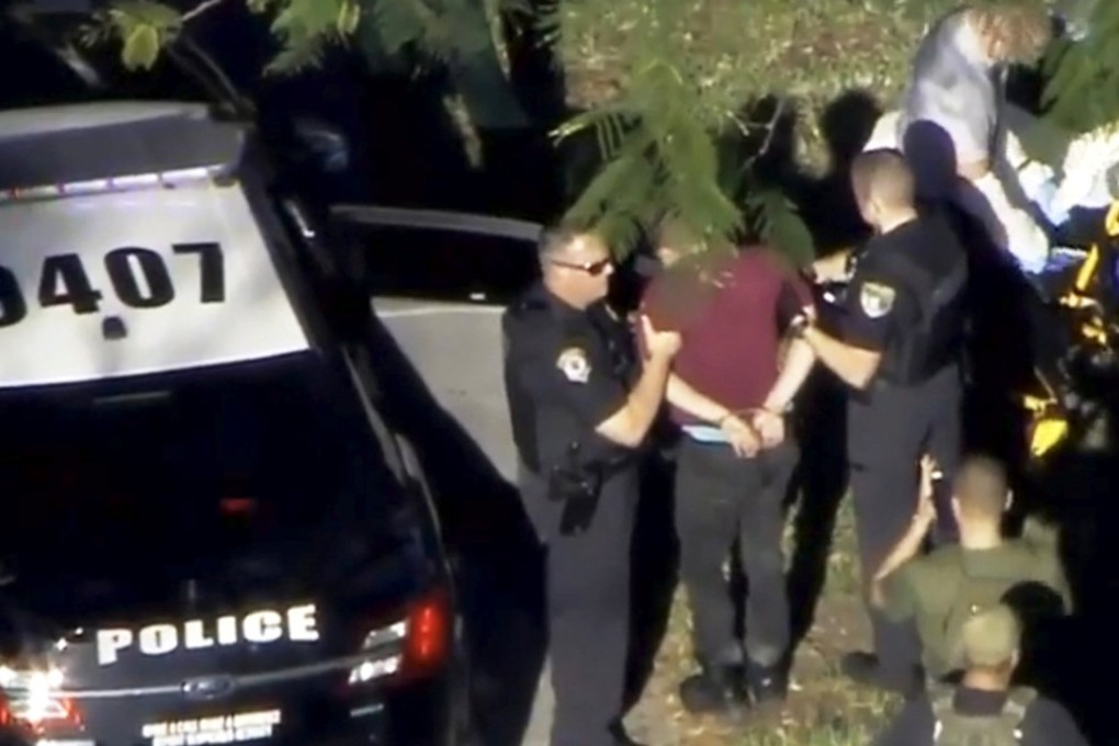 A man placed in handcuffs is led by police near Marjory Stoneman Douglas High School following a shooting incident in Parkland, Florida, on Wednesday. Police said the suspect was a 19-year-old former student at the school. Video still: WSVN.com via REUTERS
