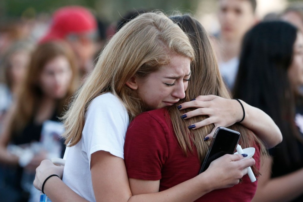 Mourners grieve as they await the start of a candlelight vigil for victims of the Marjory Stoneman Douglas High School shooting in Parkland, Florida. Photo: AP