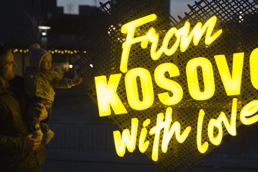 A father holds his baby next to an illuminated sign in the main square of Kosovo’s capital Pristina, Kosovo celebrated its 10th anniversary of independence on Saturday. Photo: AP