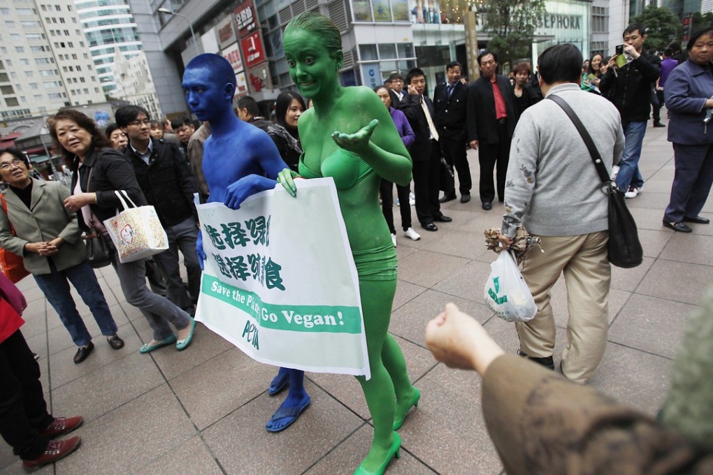 Two members of People for the Ethical Treatment of Animals march down Nanjing Street in Shanghai holding a banner reading ‘Save the Planet, Go Vegan’ in November 2011. Photo: AP
