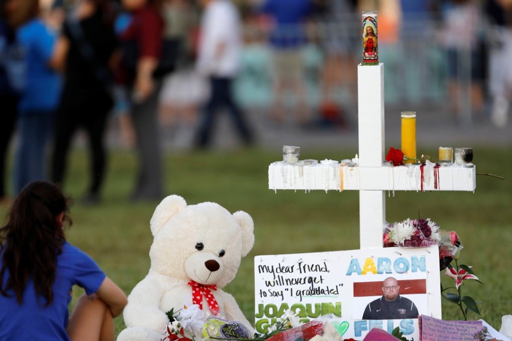 A mourner sits by a cross at a memorial for victims of the shooting at Marjory Stoneman Douglas High School in Parkland, Florida, US. Photo: Reuters
