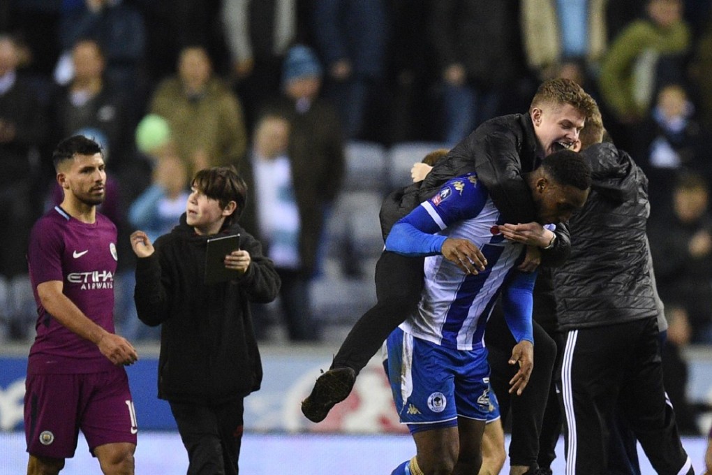 Sergio Aguero (left) walks off as supporters invade the pitch after Wigan’s FA Cup win against Manchester City. Photo: AFP