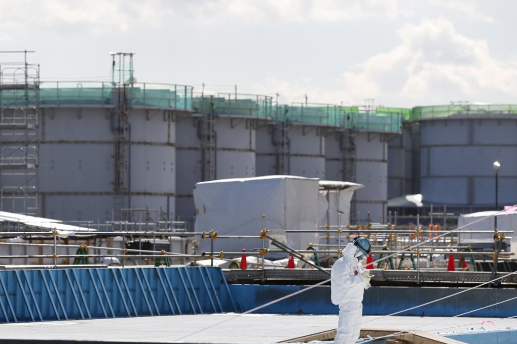 A worker, wearing a protective suit and mask, takes notes in front of storage tanks for radioactive water at Tokyo Electric Power Co's (TEPCO) tsunami-crippled Fukushima Daiichi nuclear power plant. Photo: Reuters