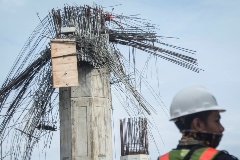 A worker stands near a collapsed girder pole on the construction site of the Bekasi-Cawang toll overpass in Jakarta, Indonesia Photo: Reuters